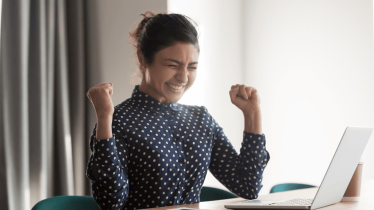 woman at computer excited about the roi of financial wellness that she implemented in 2024
