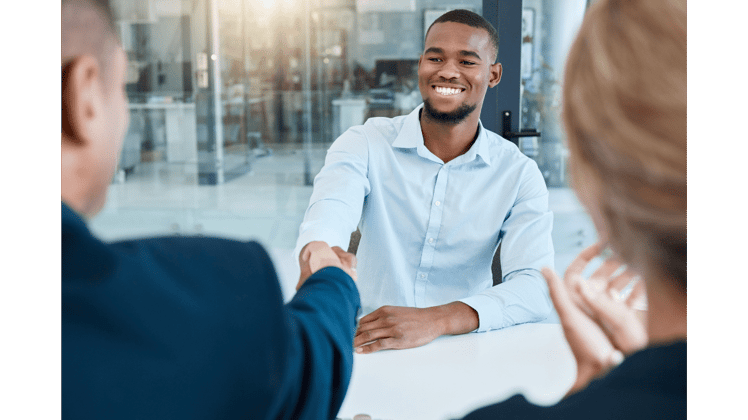 newly hired employee excitedly shaking the hand of his interviewers
