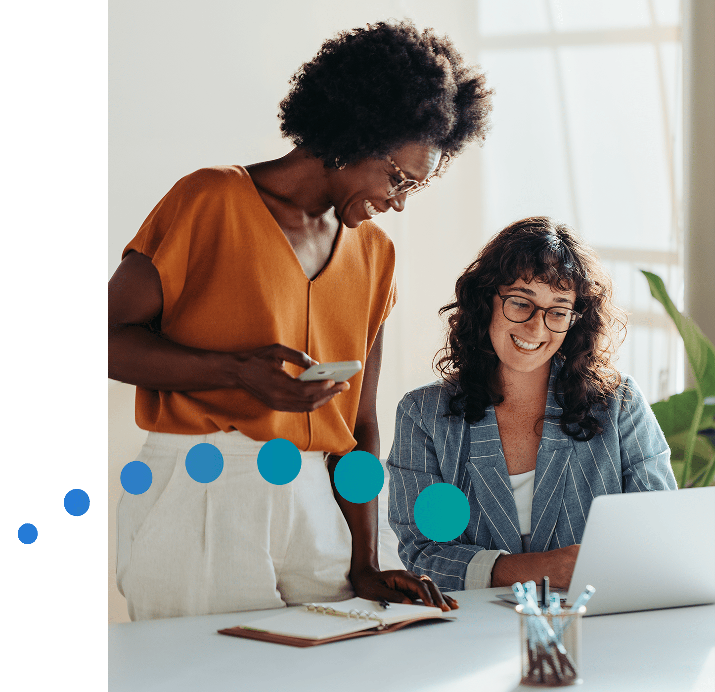Two smiling women looking at financial solutions on computer